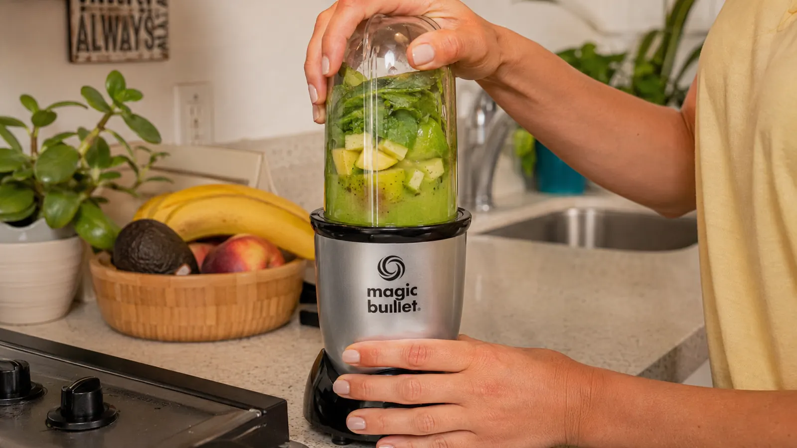 Hand placing Magic Bullet cup onto base to blend a green smoothie