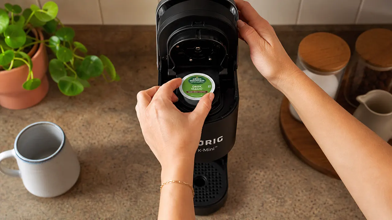 Hand inserting a K-Cup pod into the Keurig K-Mini brew chamber