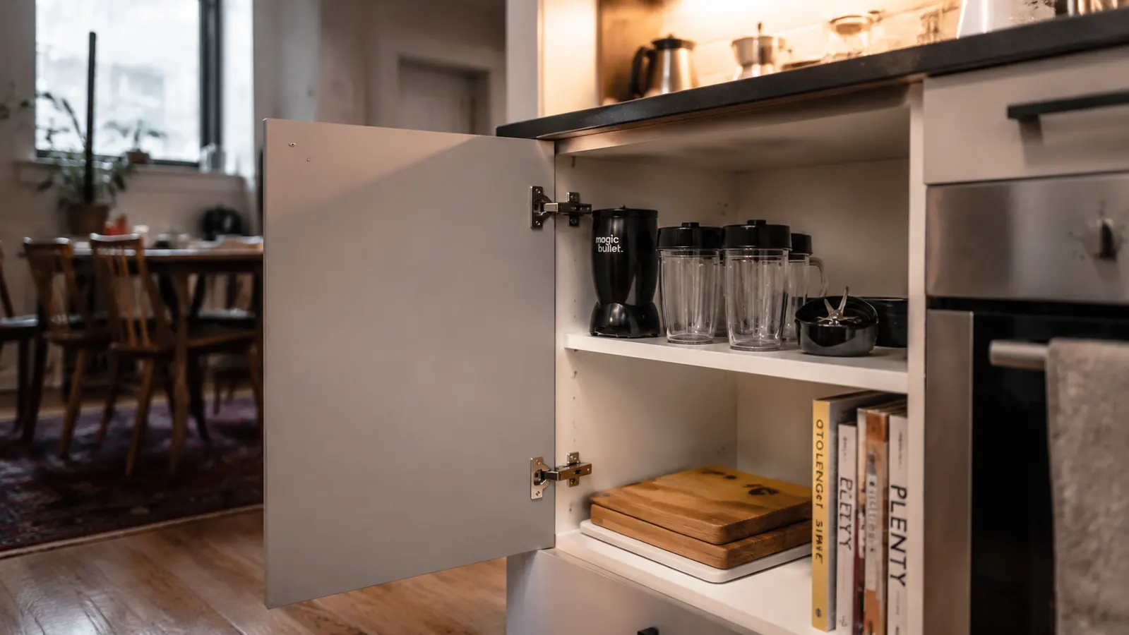 Magic Bullet blender cups stored in a kitchen cabinet alongside other small appliances